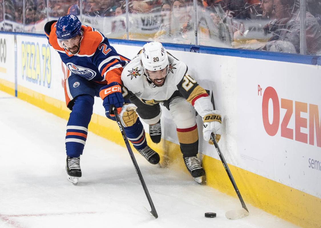 Vegas Golden Knights' Chandler Stephenson (20) and Edmonton Oilers' Evan Bouchard (2) reach for ...