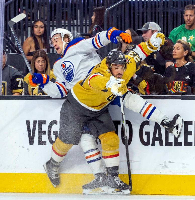 Golden Knights defenseman Alec Martinez (23) drives Edmonton Oilers center Ryan McLeod (71) int ...