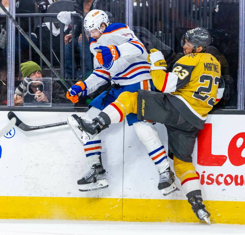 Golden Knights defenseman Alec Martinez (23) checks Edmonton Oilers left wing Warren Foegele (3 ...