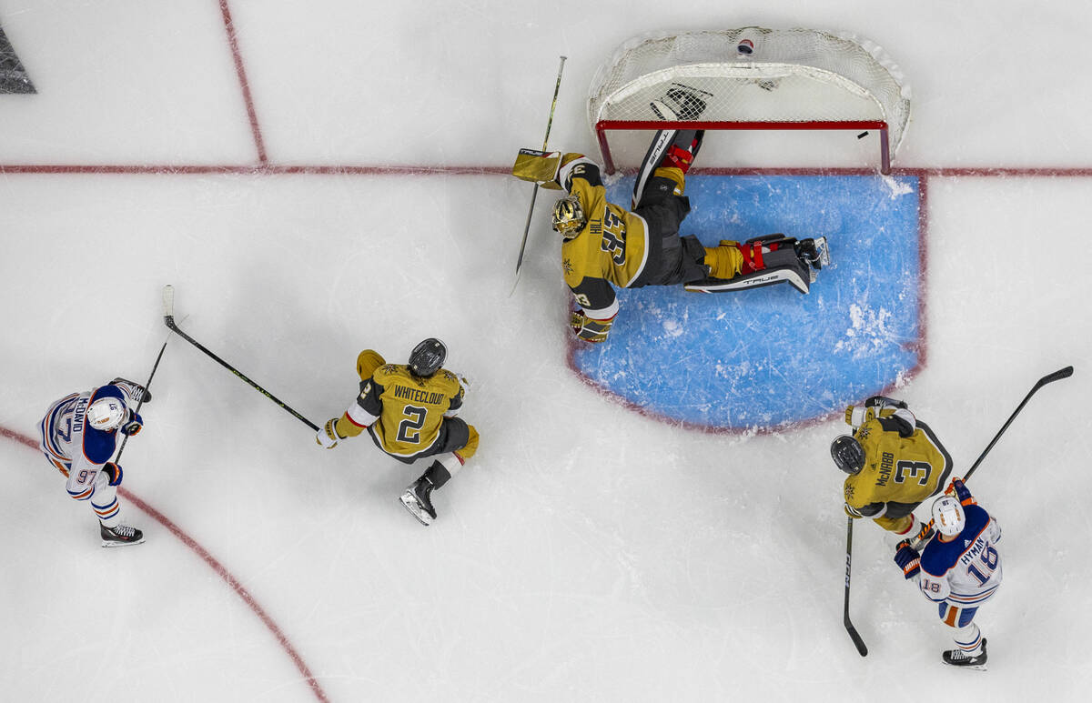 Golden Knights goaltender Adin Hill (33) misses a diving block as Edmonton Oilers center Connor ...