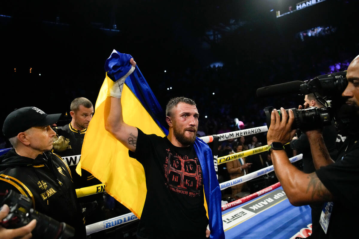 Vasiliy Lomachenko holds up his Ukrainian flag after an undisputed lightweight championship box ...