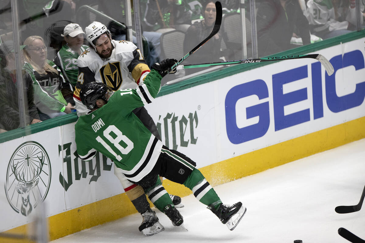 Golden Knights defenseman Nicolas Hague (14) takes a hit from Dallas Stars center Max Domi (18) ...