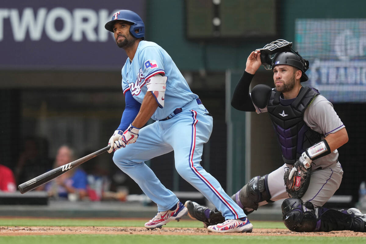 Texas Rangers' Marcus Semien, left, and Colorado Rockies catcher Austin Wynns watch Semien's do ...