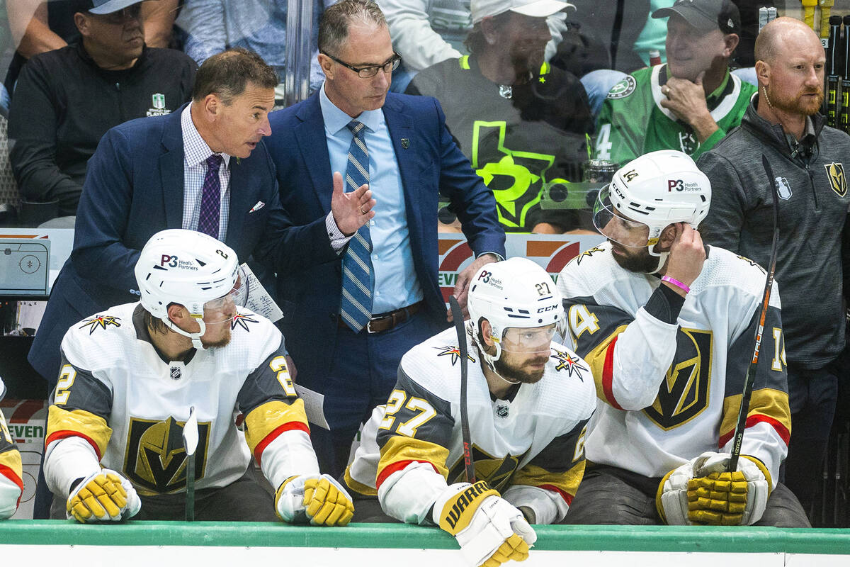 Golden Knights head coach Bruce Cassidy confers with defenseman Nicolas Hague (14) on the team ...