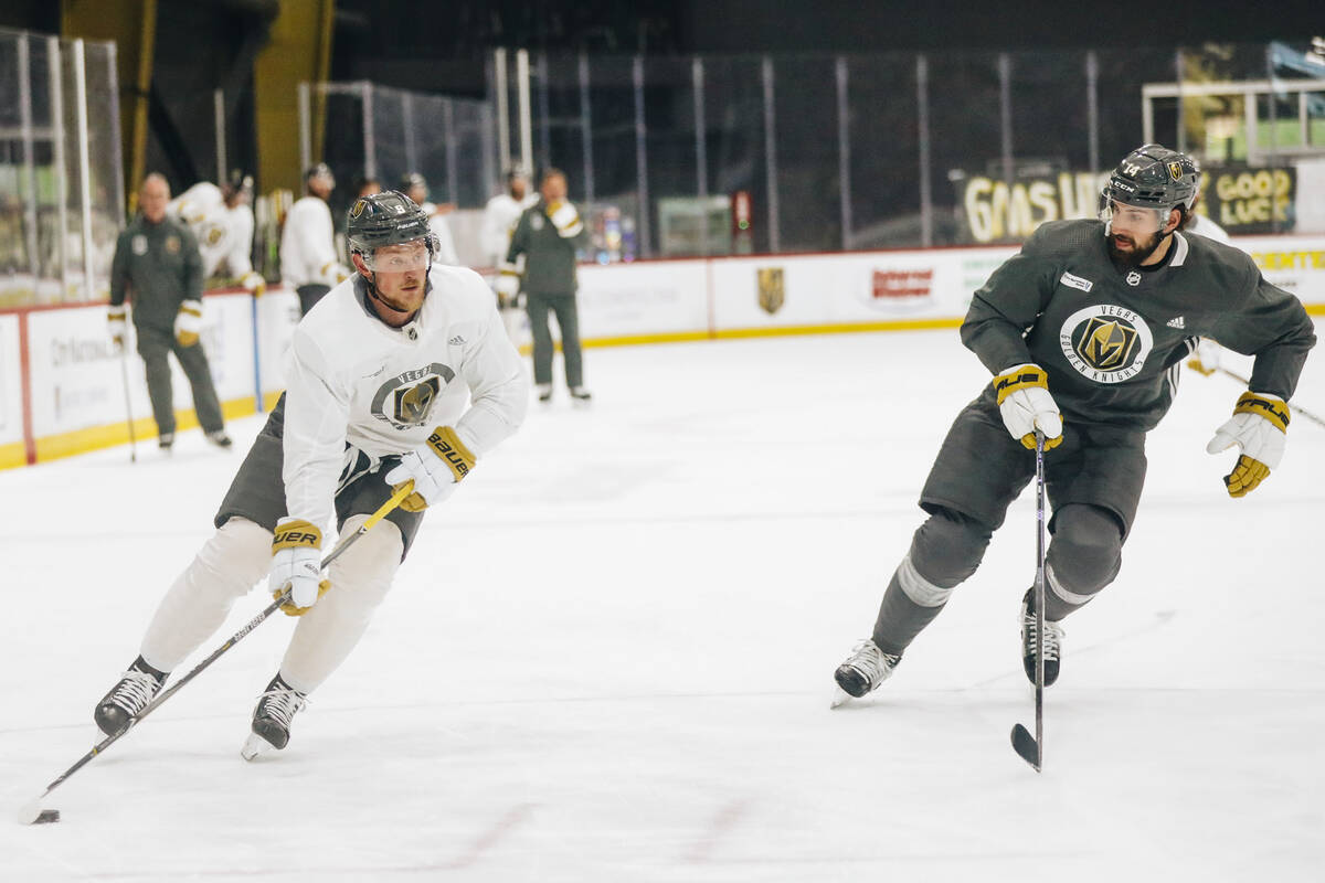 Golden Knights center Jack Eichel, left, practices shooting the puck as defenseman Nicolas Hagu ...