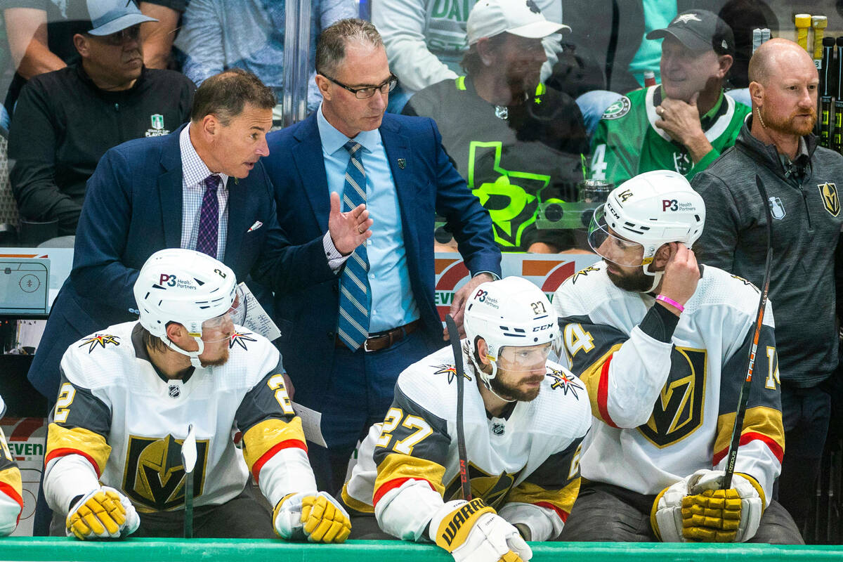 Golden Knights head coach Bruce Cassidy confers with defenseman Nicolas Hague (14) on the team ...