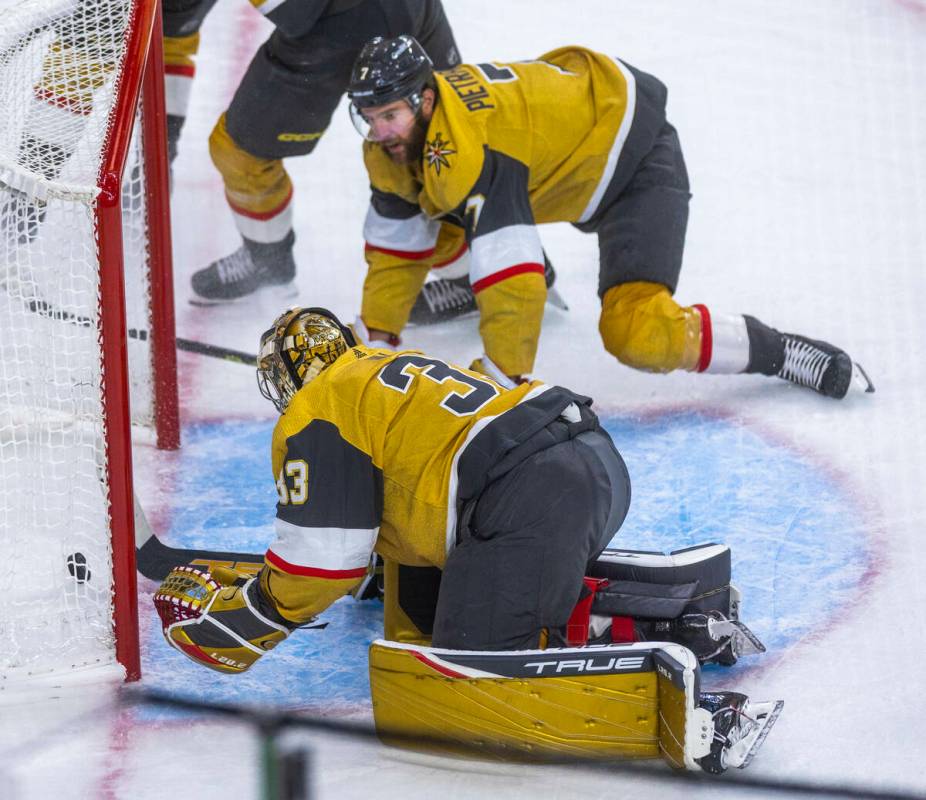 Golden Knights goaltender Adin Hill (33) has the puck slide by as teammate defenseman Alex Piet ...