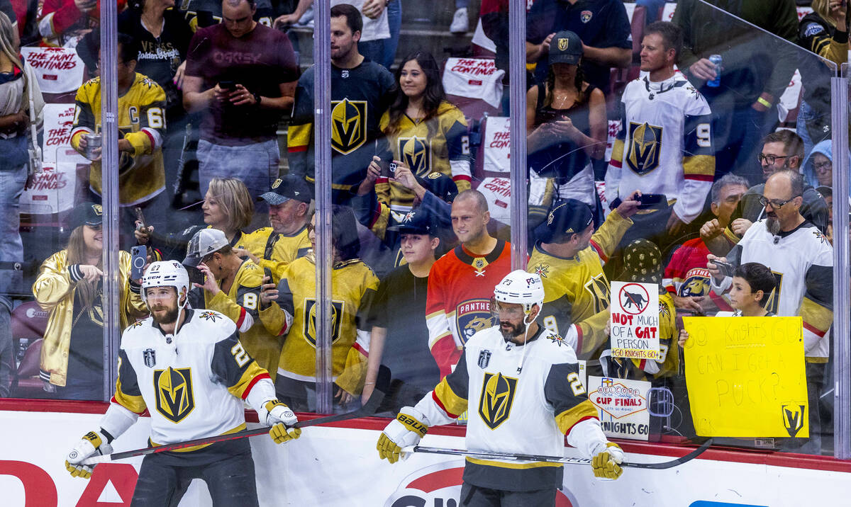 Golden Knights defenseman Shea Theodore (27) and defenseman Alec Martinez (23) stand by as fans ...