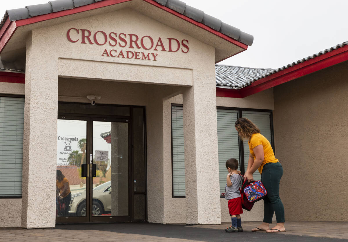 A mother walks her son into the Crossroads Academy preschool on Wednesday, June 7, 2023, in Las ...