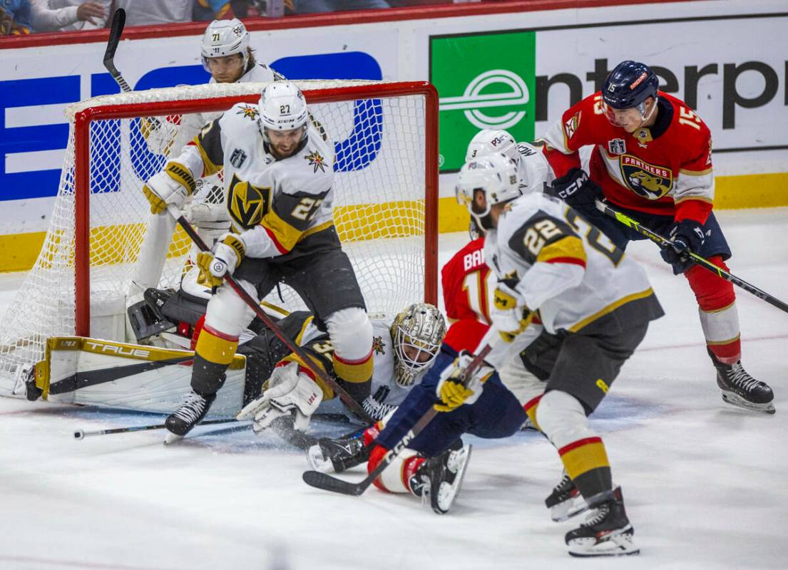 Golden Knights goaltender Adin Hill (33) and defenseman Shea Theodore (27) combine to save the ...