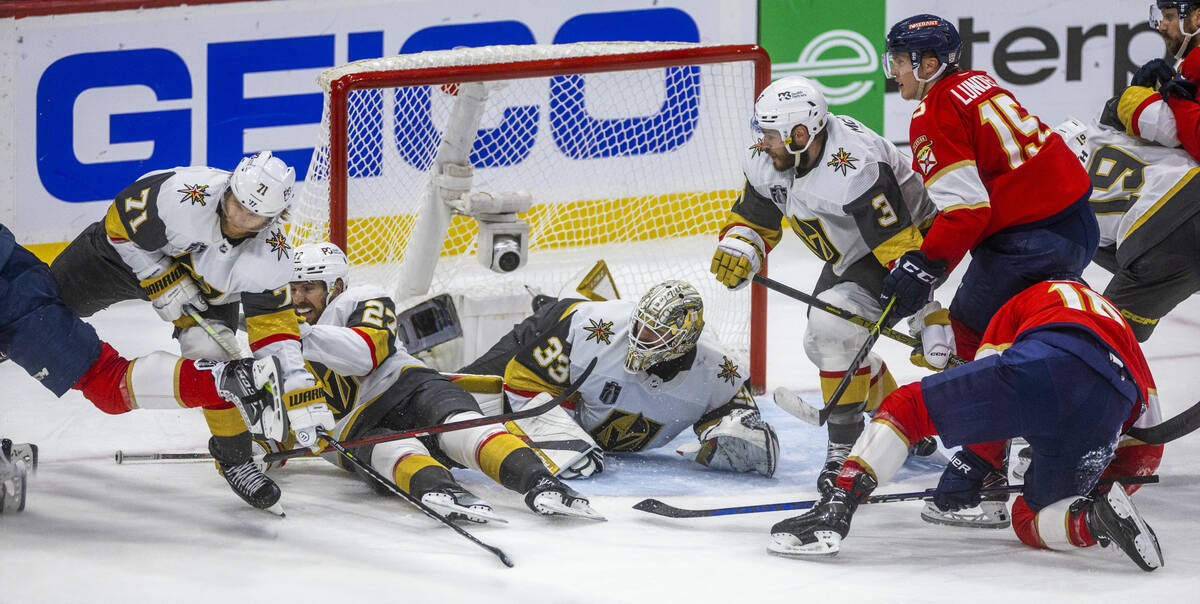 Golden Knights goaltender Adin Hill (33) and defenseman Shea Theodore (27) combine to save the ...