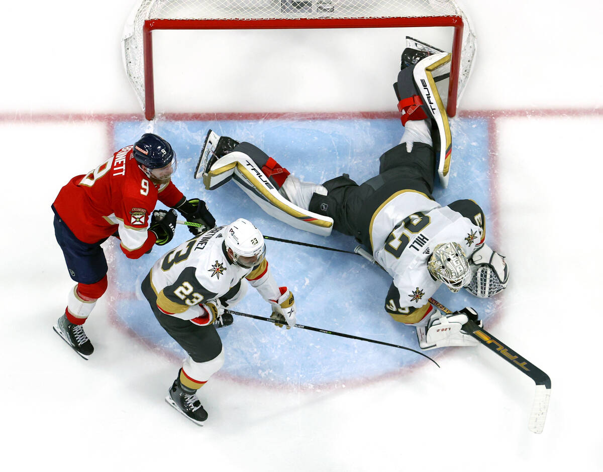 Golden Knights goaltender Adin Hill (33) dives for a puck with teammate defenseman Alec Martine ...