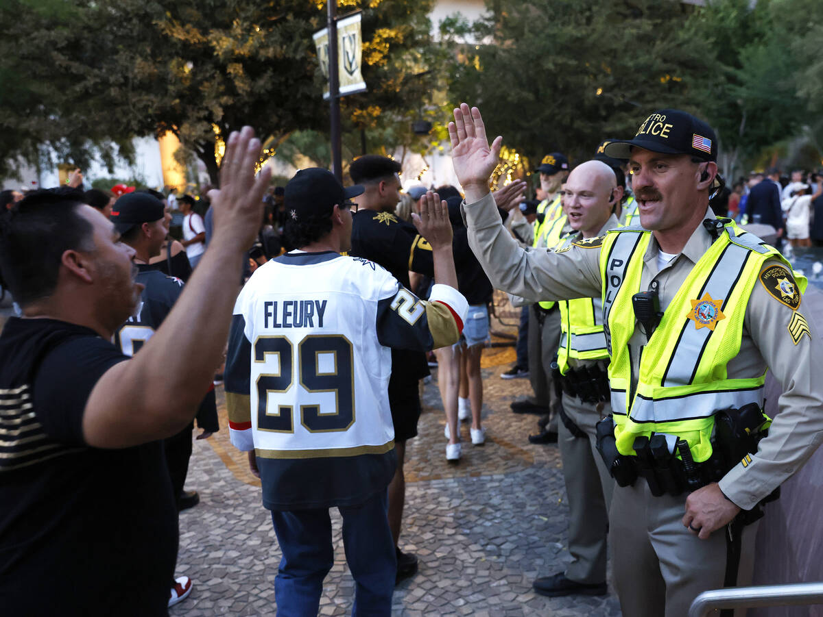 Golden Knights fans and Las Vegas police officers exchange high-fives their team''s Stanley Cup ...