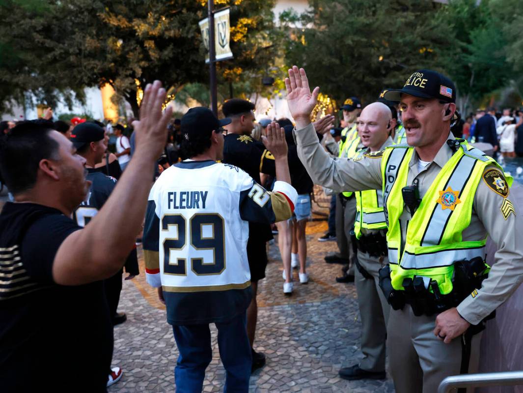 Golden Knights fans and Las Vegas police officers exchange high-fives after the team's Stanley ...