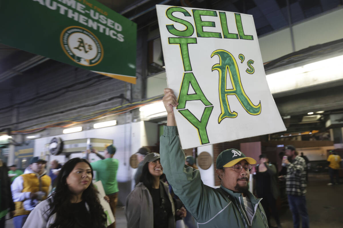 A fan holds a sign to protest the Oakland Athletics' planned move to Las Vegas, before a baseba ...