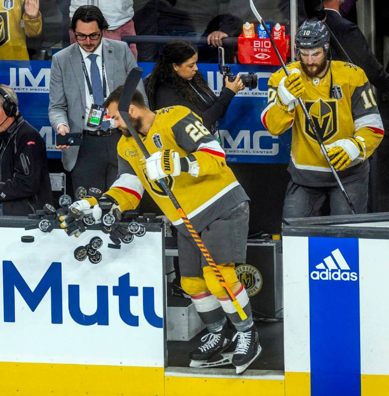 Golden Knights left wing William Carrier (28) knocks pucks off the bench rail for warmups befor ...