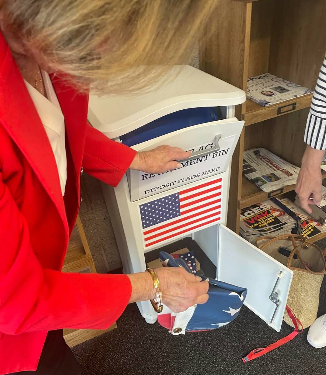 Jan Butler removes flags from the new flag disposal bin at the Paseo Verde Library on May 30. ( ...