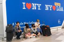 Travelers use their electronic devices while sitting on the floor of the departures area of Ter ...