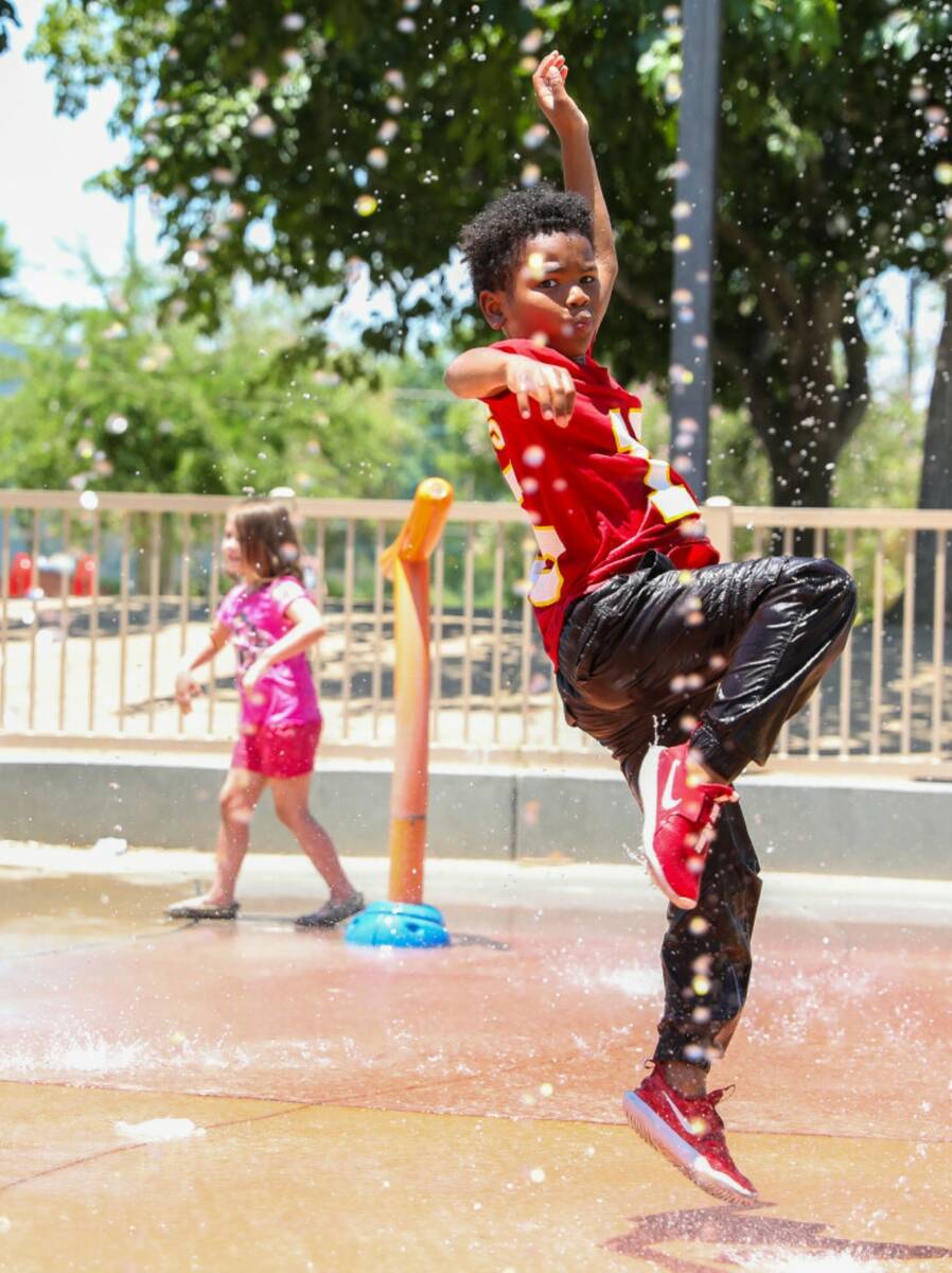 Trent Turner, 7, jumps through the water features at Bob Baskin Park to cool down during the 11 ...