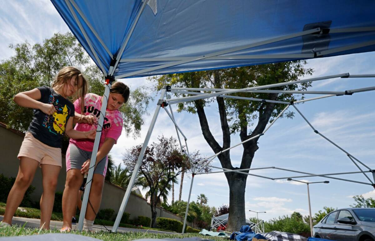 Reighn Stanford of North Las Vegas, 6, left, sets up a tent with her sister Willow, 10, Monday, ...