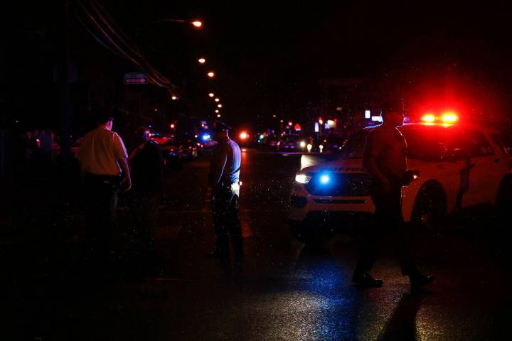 Philadelphia police stand at the intersection of 56th Street and Kingsessing Avenue after multi ...