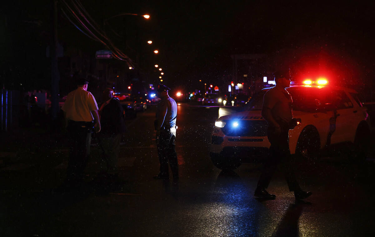 Philadelphia police stand at the intersection of 56th Street and Kingsessing Avenue after multi ...