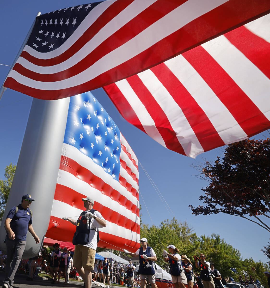 People carry a giant American flag inflatable balloon during the annual Summerlin Council Patri ...