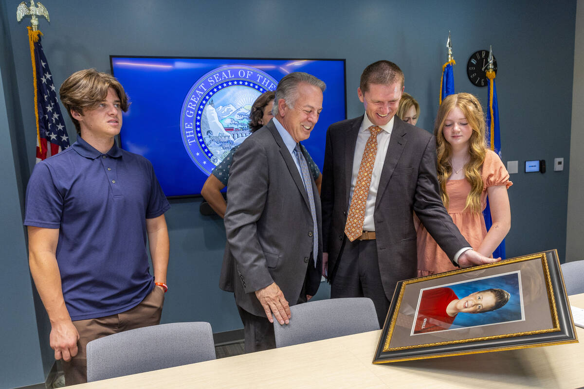 Nevada Gov. Joe Lombardo looks at a photo of Rex Patchett held by his father Jason Patchett joi ...