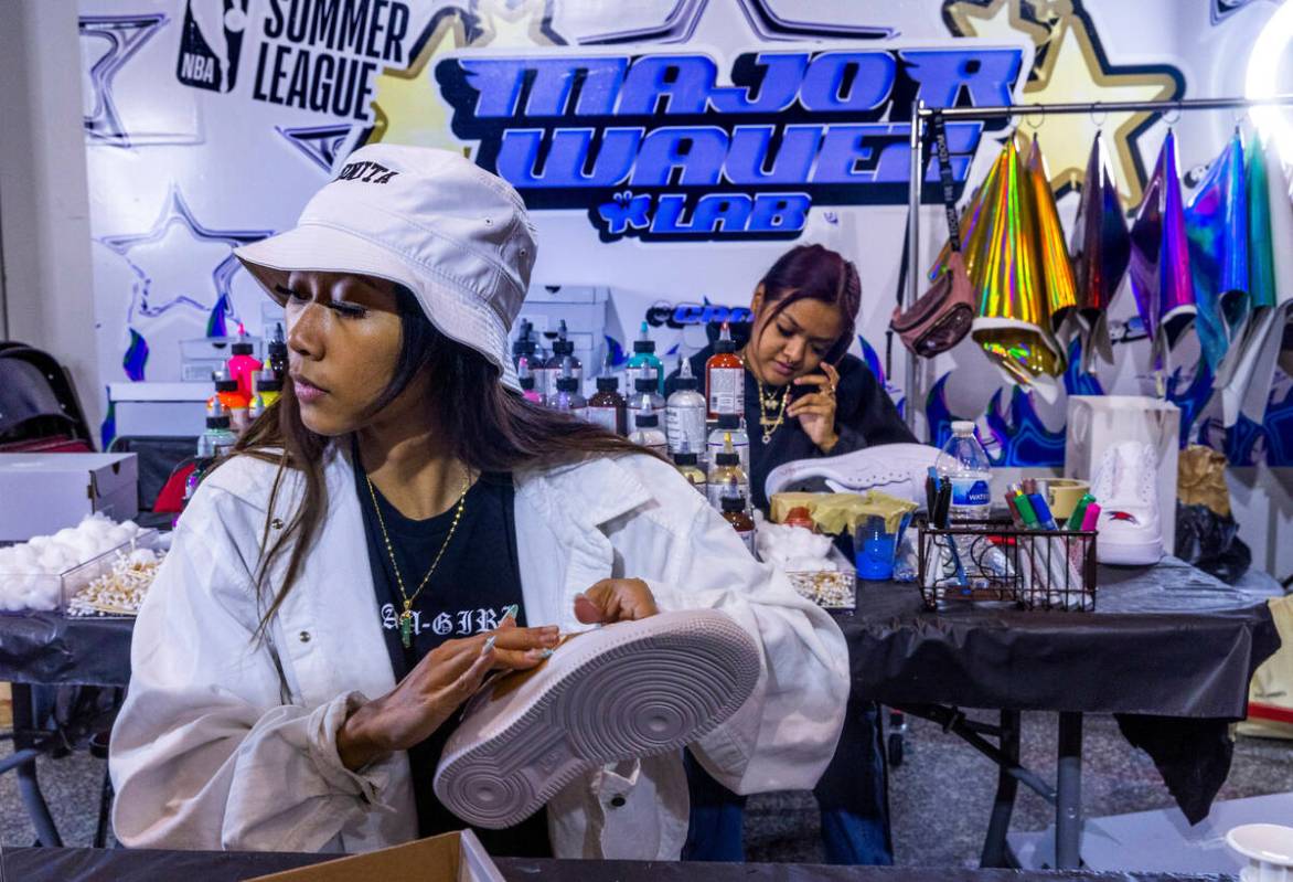 Nikki Roxas, left, attaches a custom pattern to a sneaker as Myah Alvarado paints one in the M ...