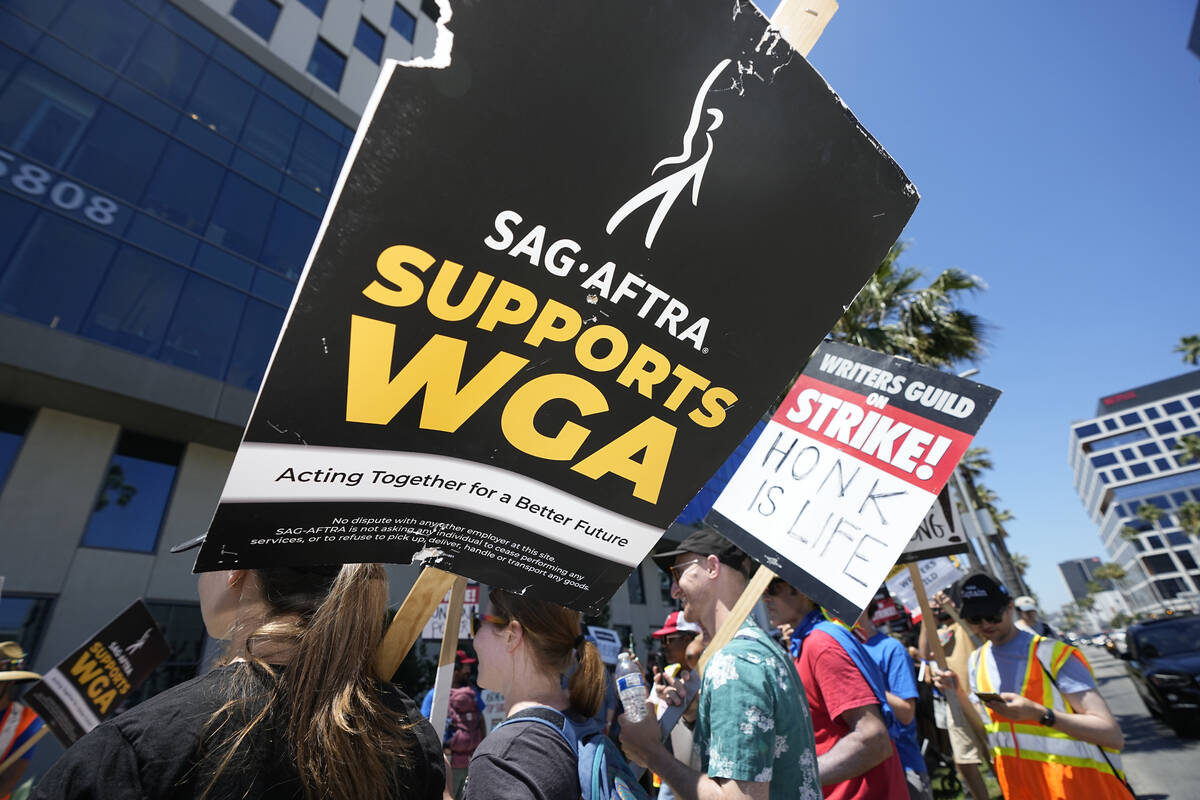 Picketers carry signs outside Netflix during a Writers Guild rally on Thursday, July 13, 2023, ...