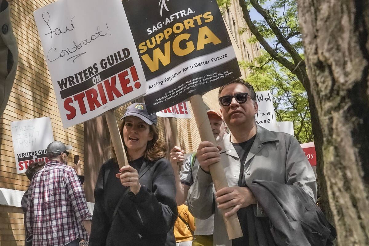 FILE - Actors and comedians Tina Fey, center, and Fred Armisen, right, join striking members of ...