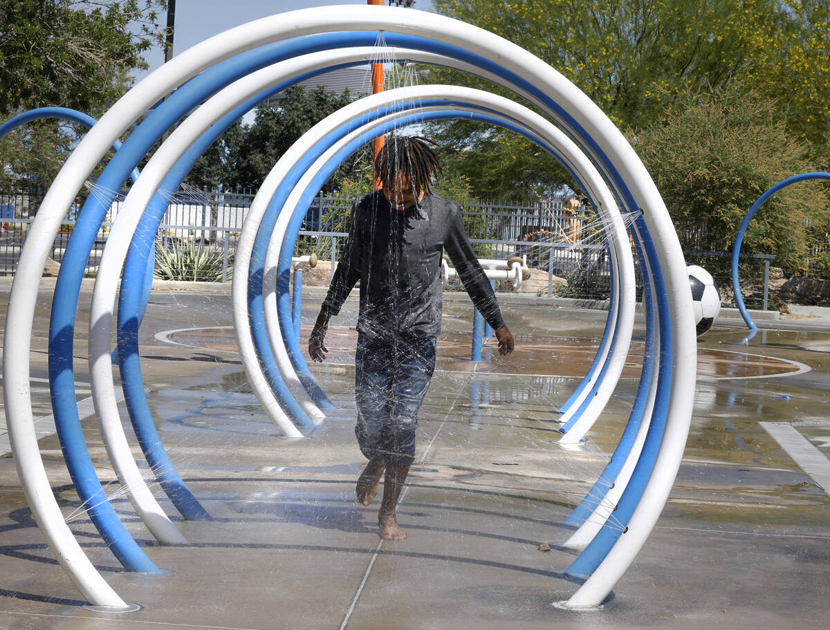 Samuel Lee Jones of Las Vegas runs through the water at Baker Park’s splash pad, Friday, ...