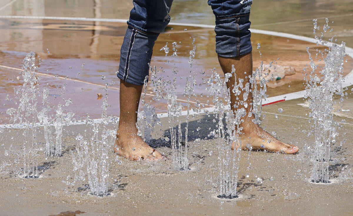 Samuel Lee Jones of Las Vegas runs through the water at Baker Park’s splash pad, Friday, ...