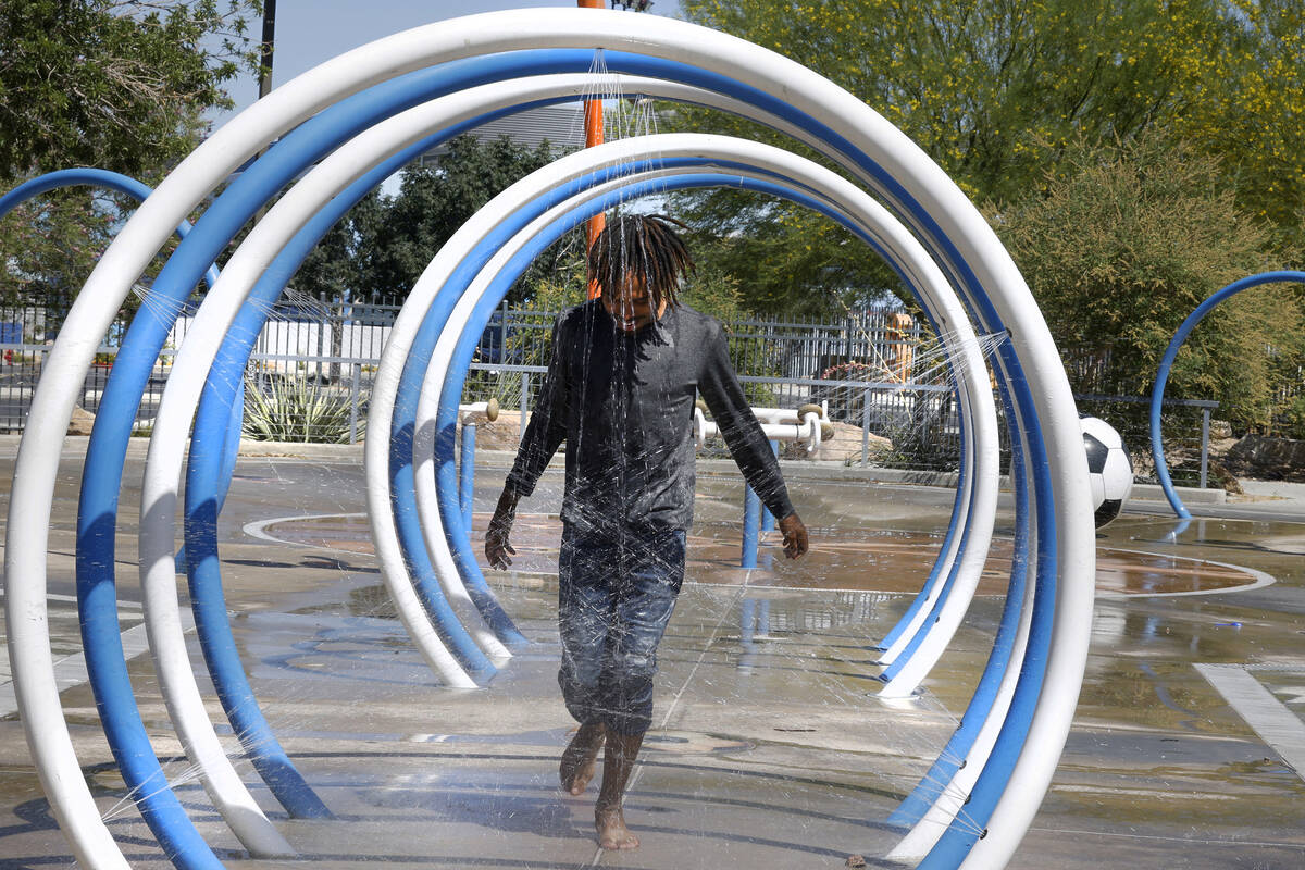 Samuel Lee Jones of Las Vegas runs through the water at Baker Park’s splash pad, Friday, ...