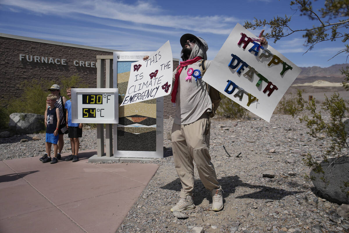 A demonstrator protests visitors to Death Valley National Park, Sunday, July 16, 2023, in Death ...