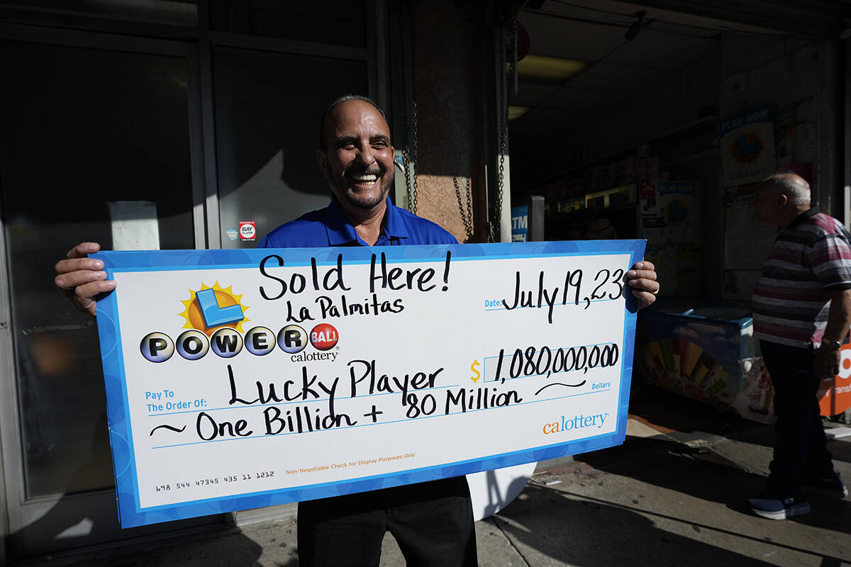 Lottery official Rick Herrera holds an enlarged check outside the Las Palmitas Mini Market wher ...