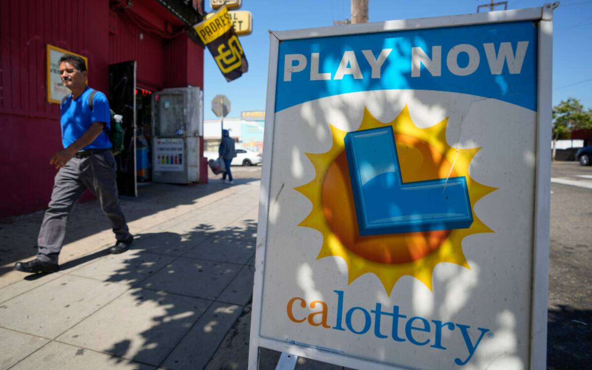 A man walks by a sign for the lottery in front of a market Tuesday, July 18, 2023, in San Diego ...