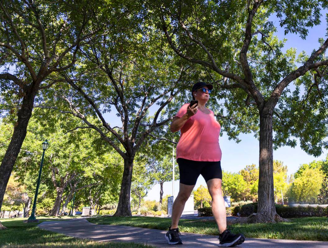 A pedestrian walks on a tree-covered sidewalk along Green Valley Parkway on Thursday, July 20, ...