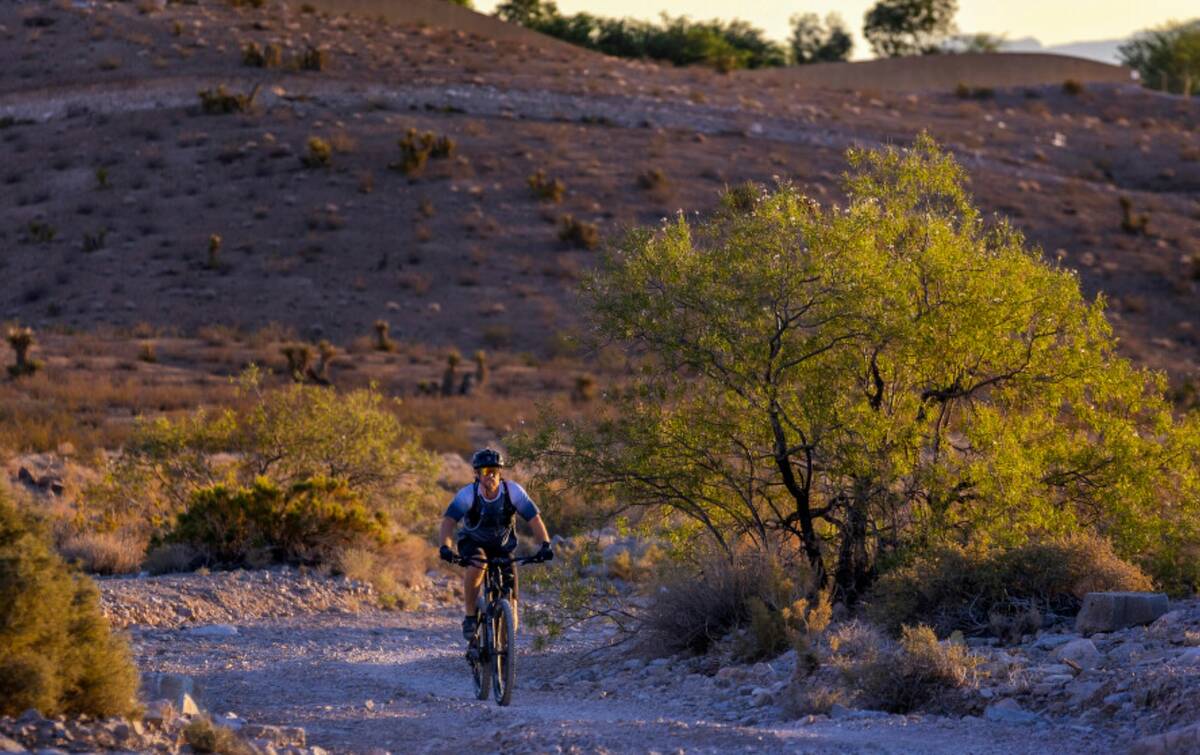 Nate Coats rides a trail in the southwest hills as the sun rises over the valley on Thursday, J ...