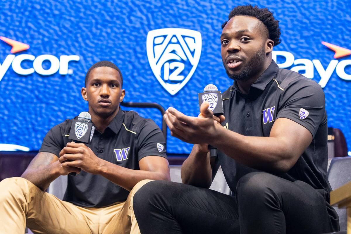 Washington Huskies quarterback Michael Penix Jr., left, listens as linebacker Edefuan Ulofoshio ...