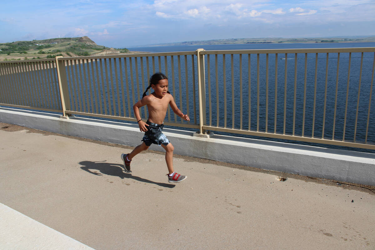A young boy runs along a bridge in New Town, North Dakota, as part of an organized health and w ...