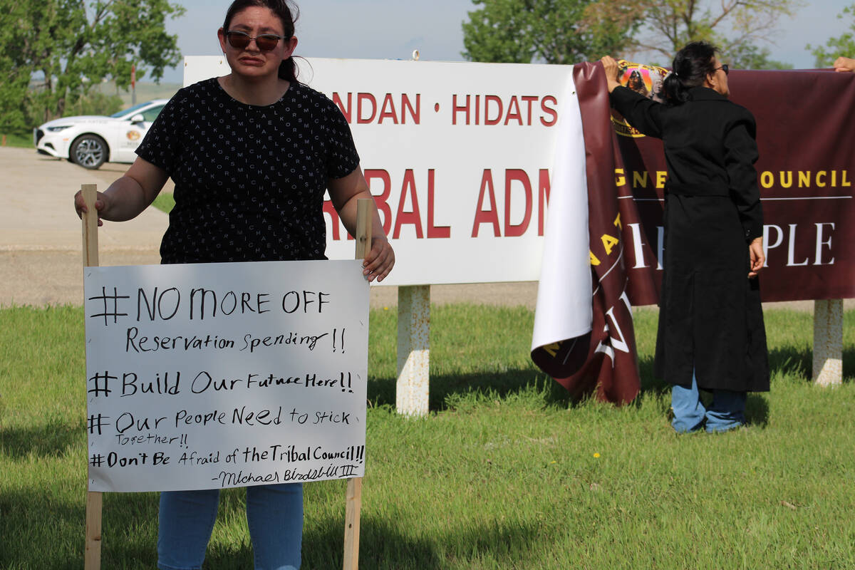A woman holds a sign at a protest outside MHA Nation tribal headquarters in New Town, North Dak ...