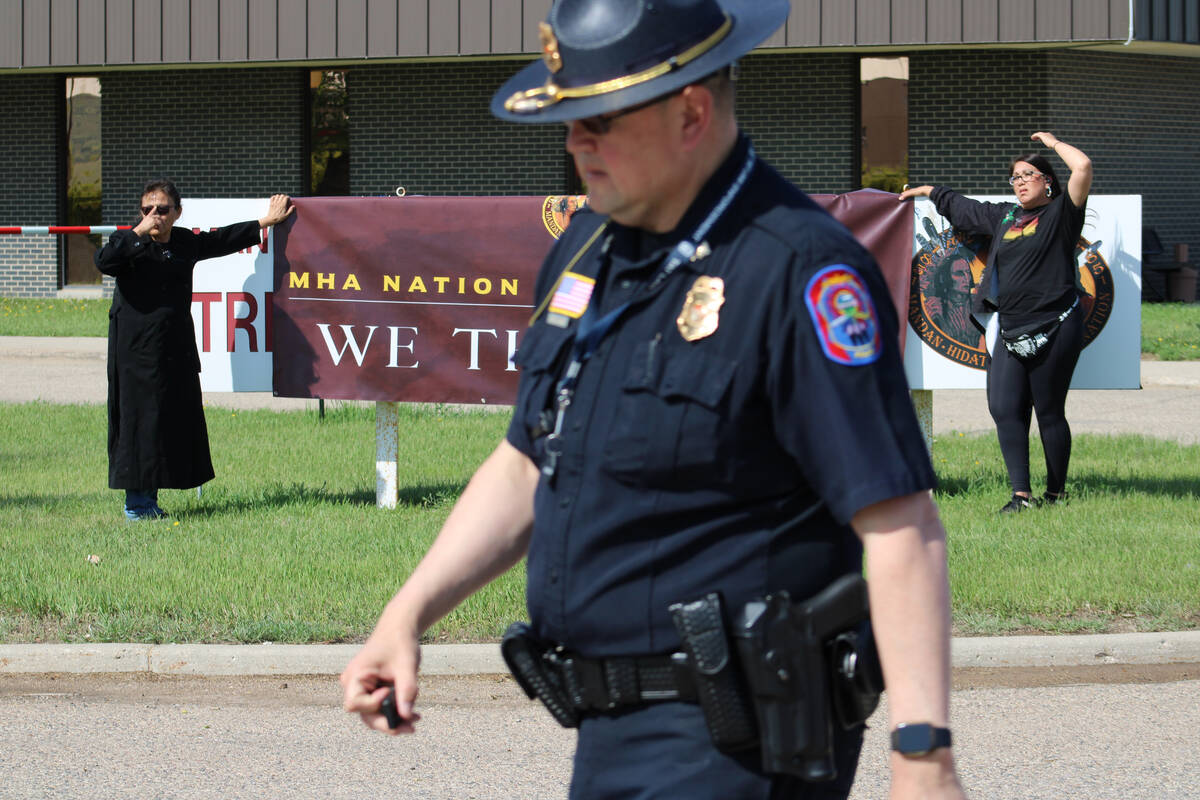 A Three Affiliated Tribes police officer walks near a protest against tribal leadership outside ...