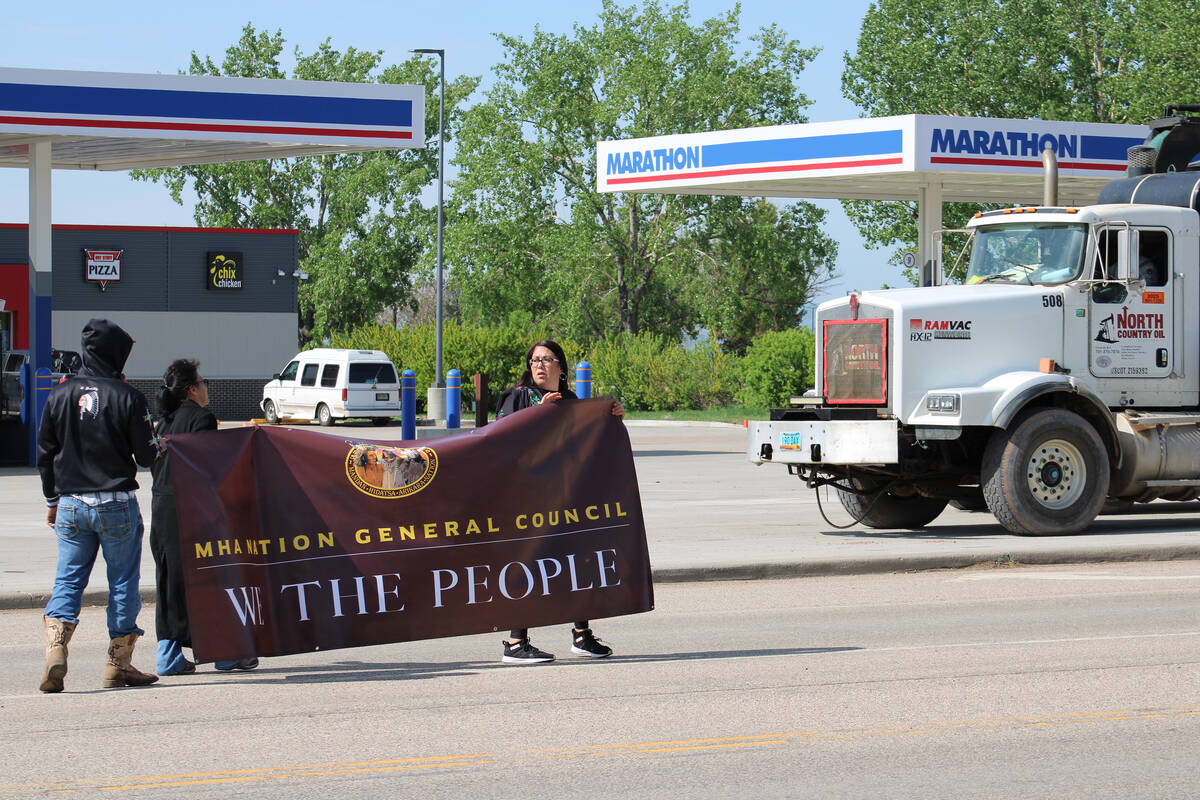 Kelly Hosie, right, holds a banner with other protestors in New Town, North Dakota, on May 27, ...