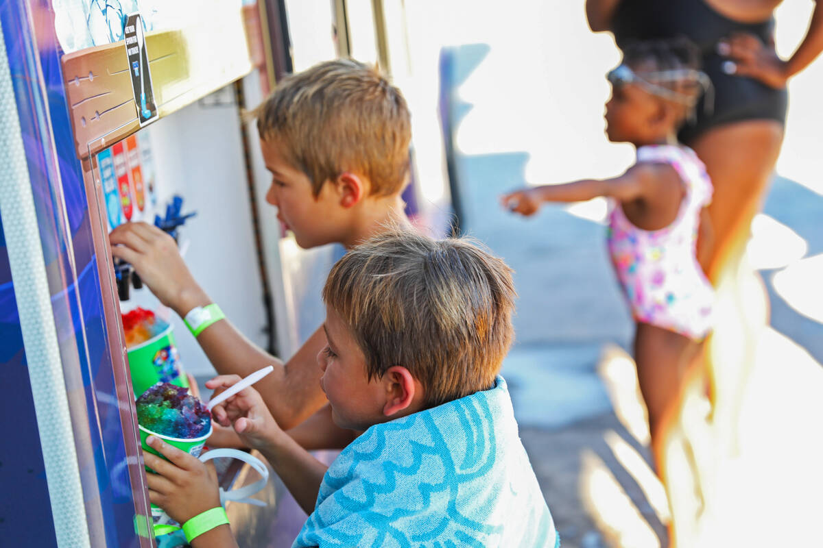 Liam Burr, left, and Aaron Burr flavor their shaved ice at the Splash Back to School Party and ...