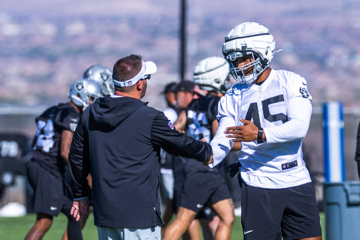 Raiders head coach Josh McDaniels talks with fullback Jakob Johnson (45) during training ...