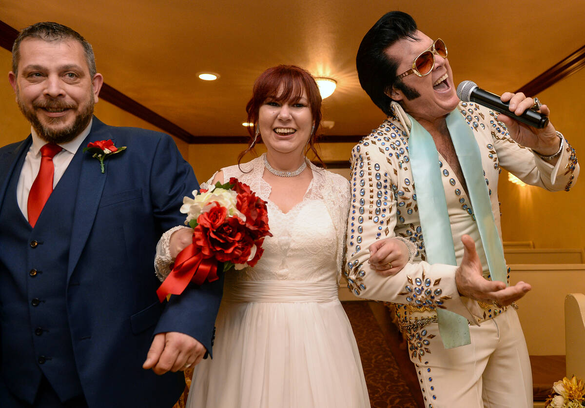 Hugo and Sally Knight from Ireland walk down the aisle with Elvis Presley impersonator Brendan ...