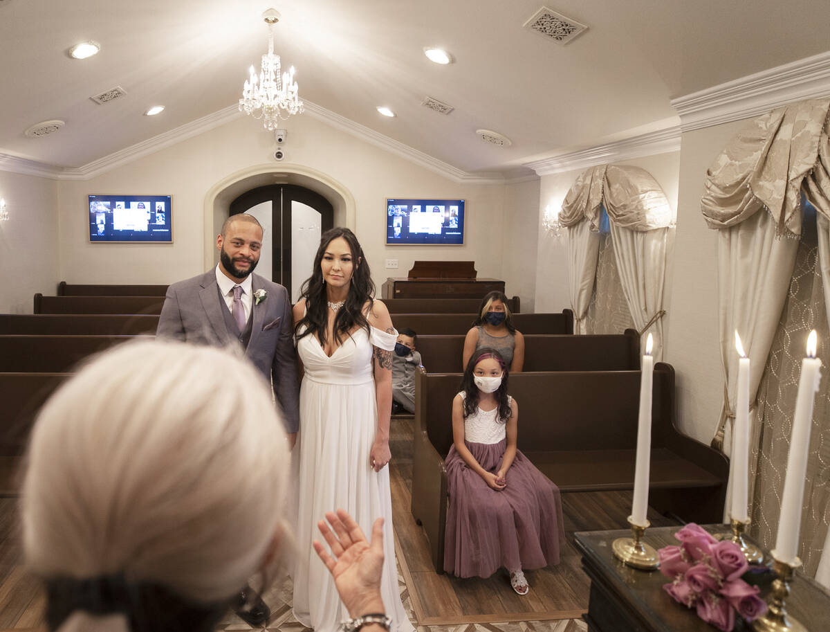 William and Brandi Alexander, from Anchorage, Alaska, listen to their officiant during a vow re ...