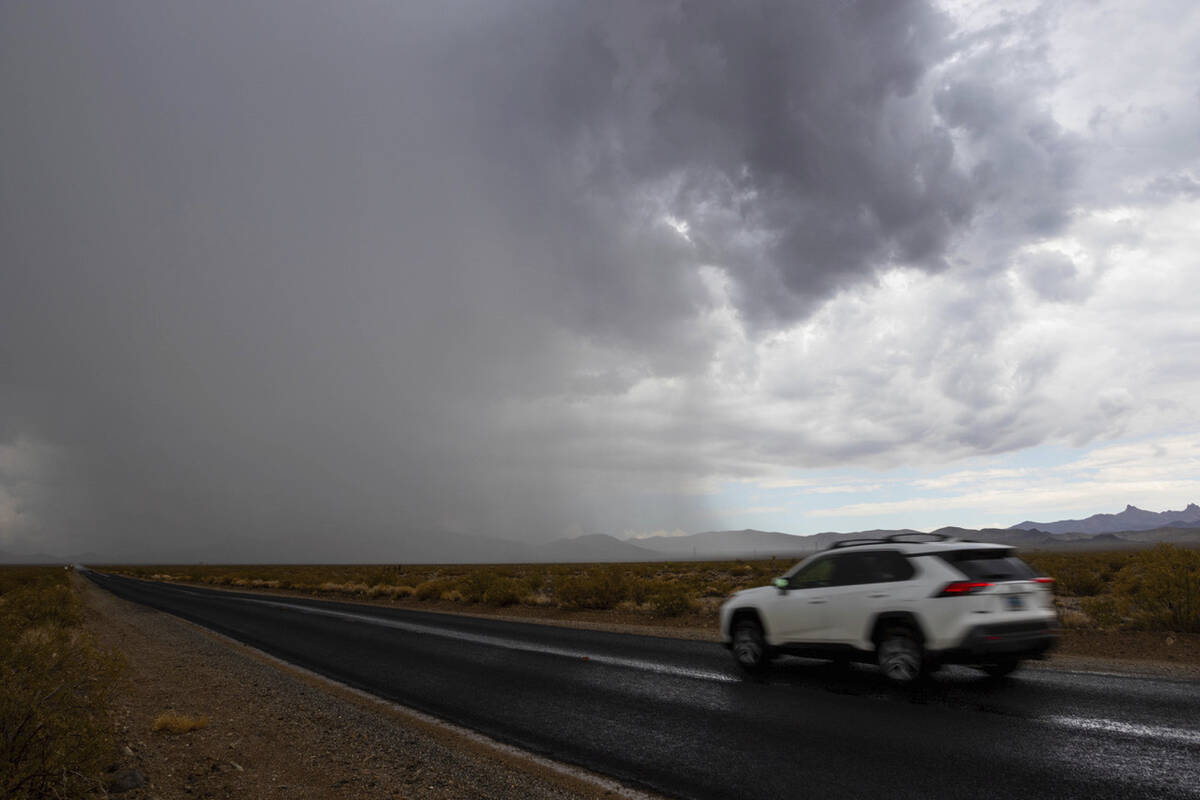 A vehicle drives down Nipton Road, as rain falls over the York Fire, Tuesday, Aug. 1, 2023, in ...