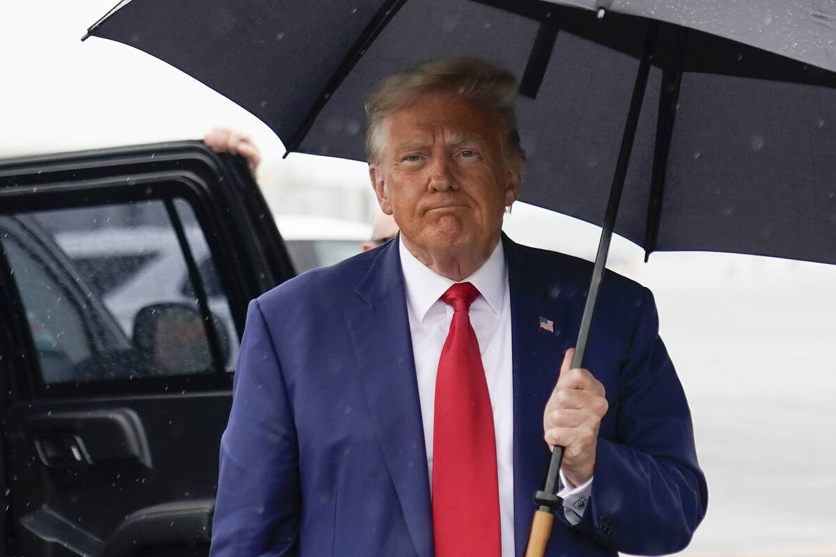 Former President Donald Trump walks over to speak with reporters before he boards his plane at ...